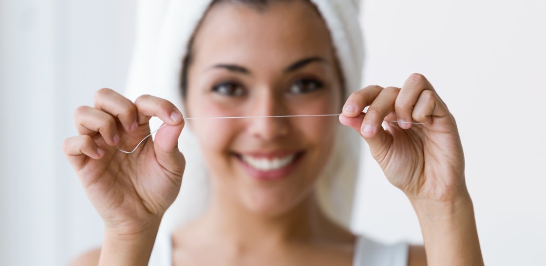 Shot of pretty young woman using dental floss in a home bathroom.