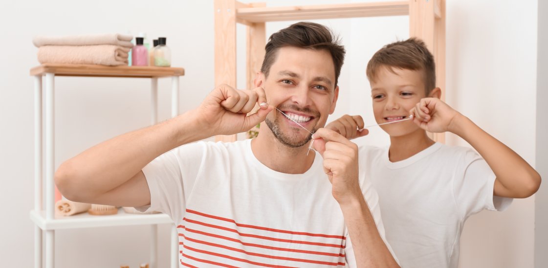 Little boy and his father flossing teeth in bathroom