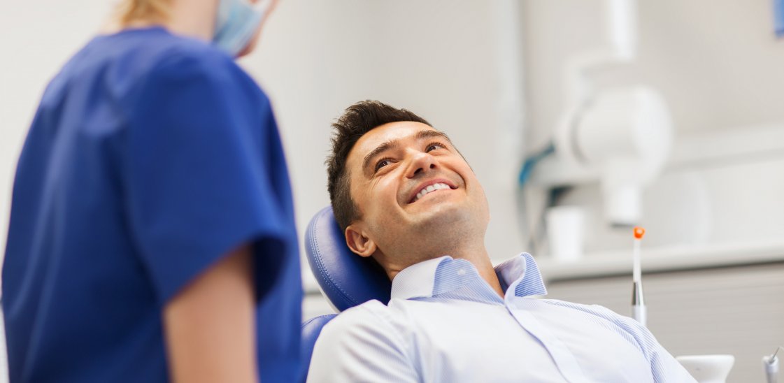 Female dentist with happy male patient at clinic