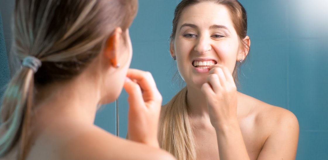 Young woman checking her teeth at mirror