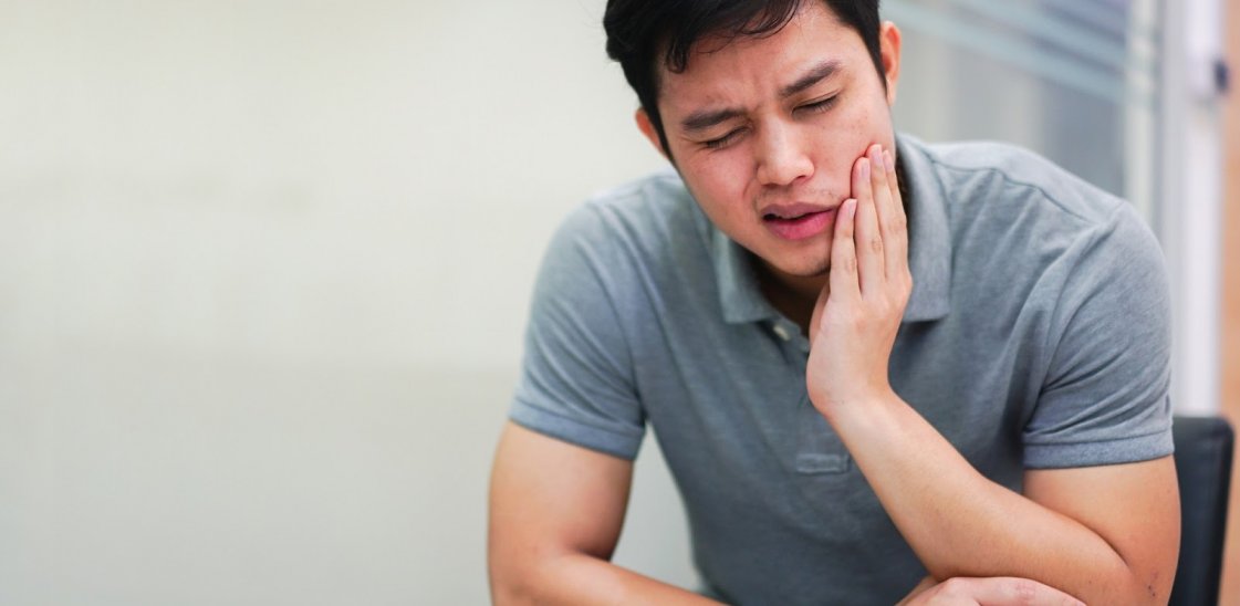 Man in pain with toothache and holding his hand on his cheek