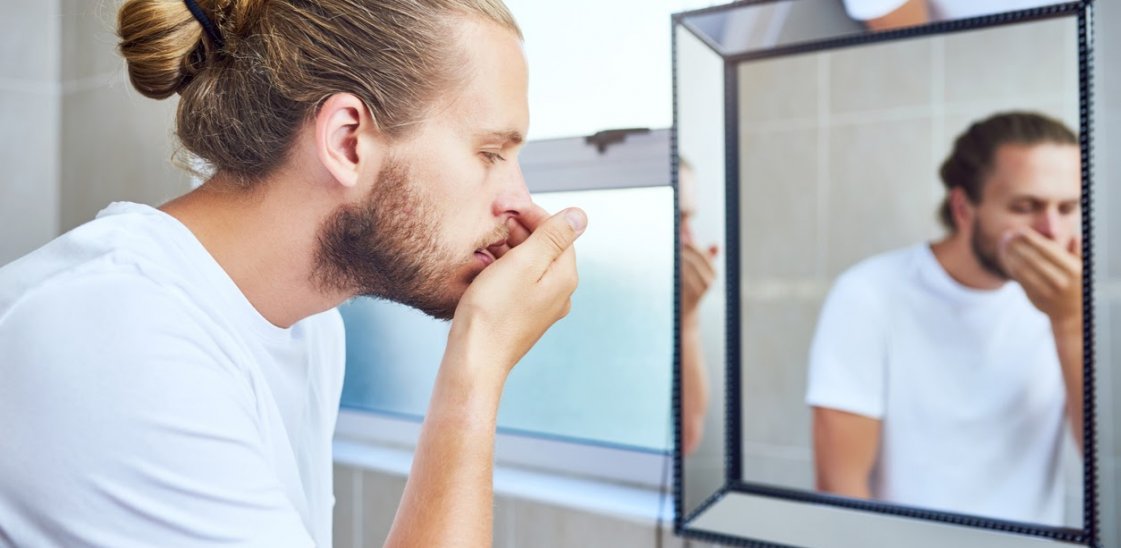 A man checking his breath for signs of halitosis