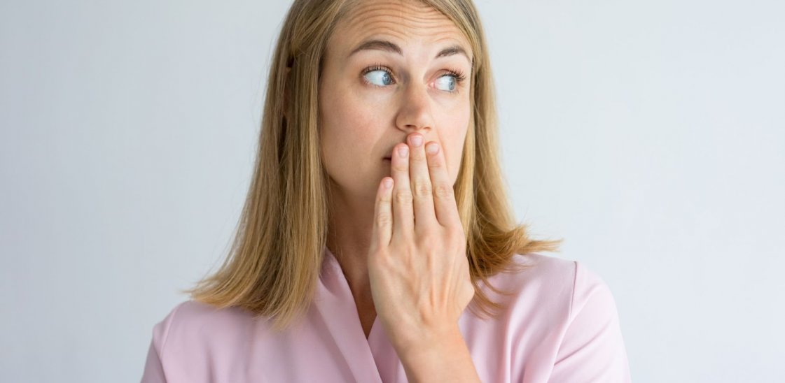 a woman with a hand over her mouth to cover bad breath