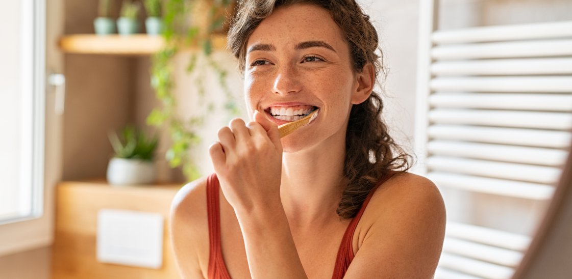 Woman brushing teeth at mirror