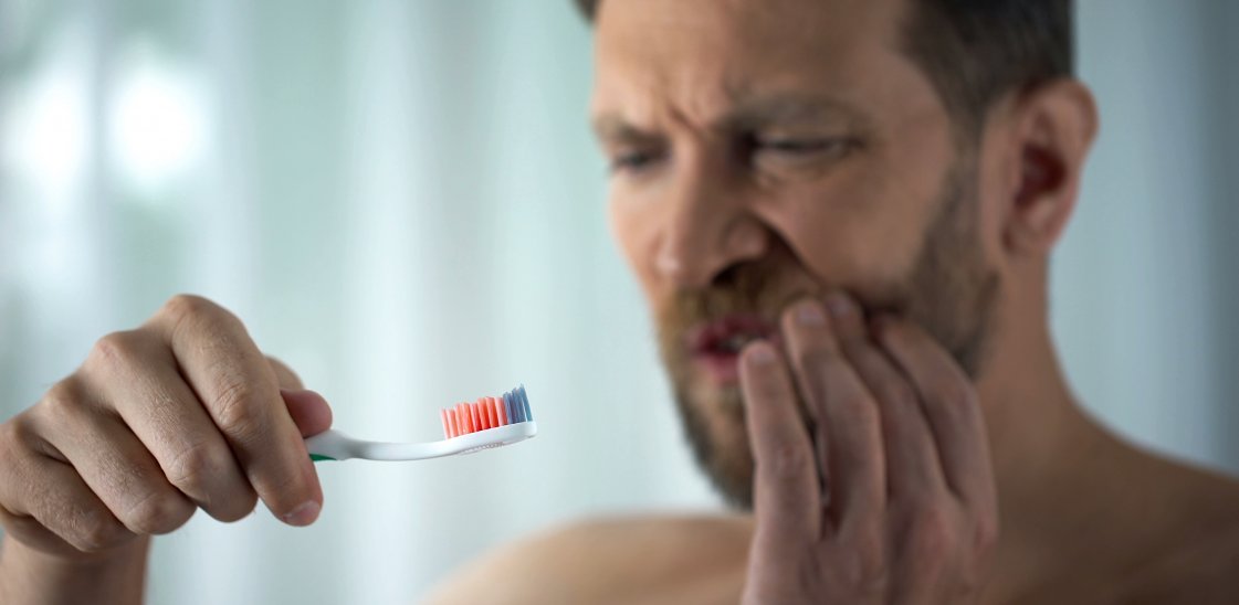 Male in bathroom looking at blood toothbrush, oral hygiene, parodontosis illness