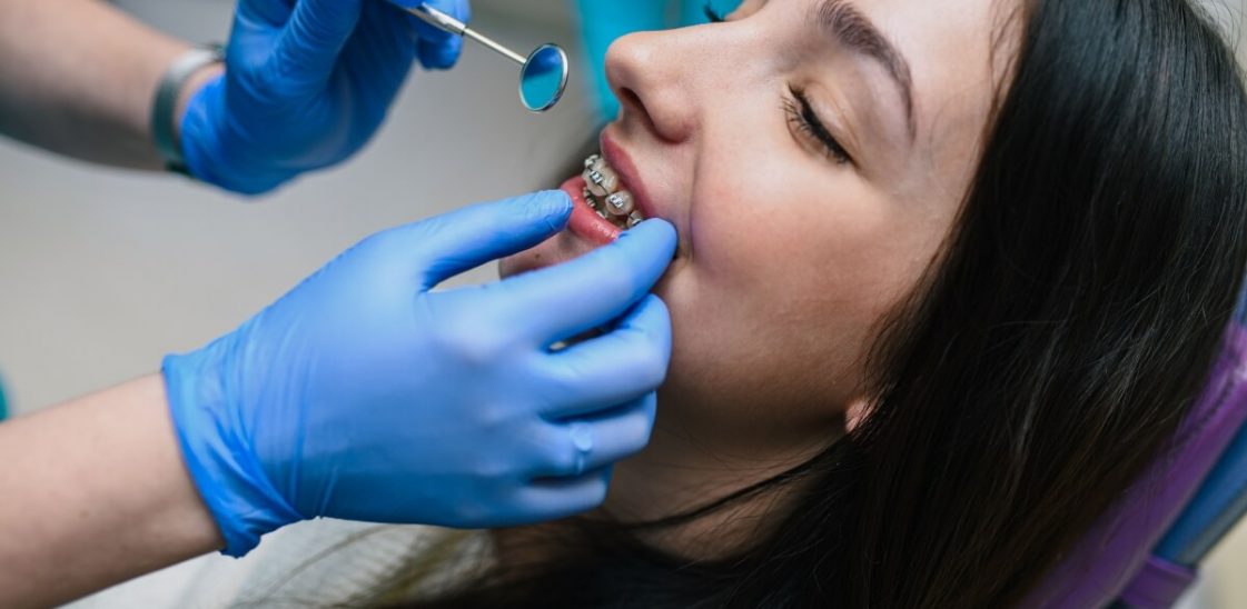 A dentist examines a woman’s braces and teeth