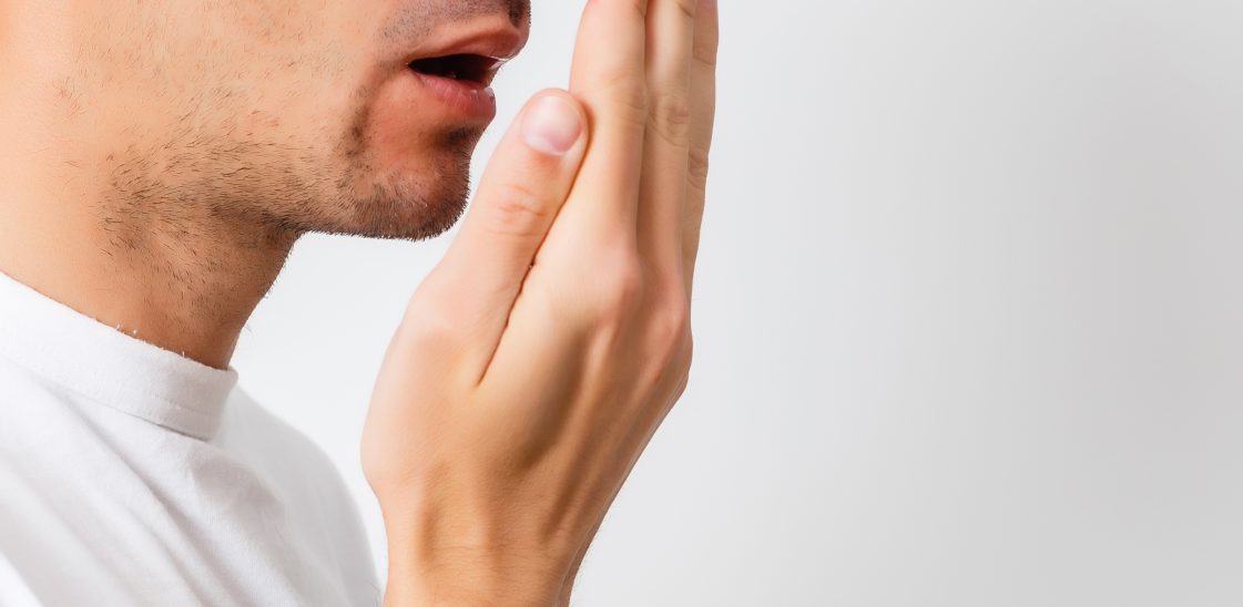 A man checks his breath against the palm of his hand.