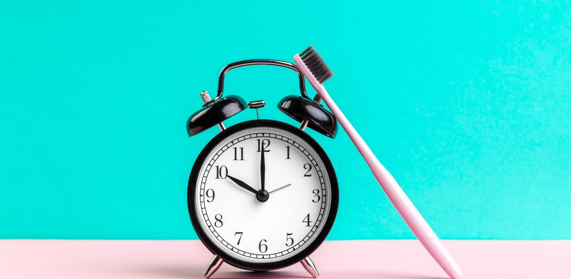 toothbrush leaning upright against alarm clock to signify dental care while fasting