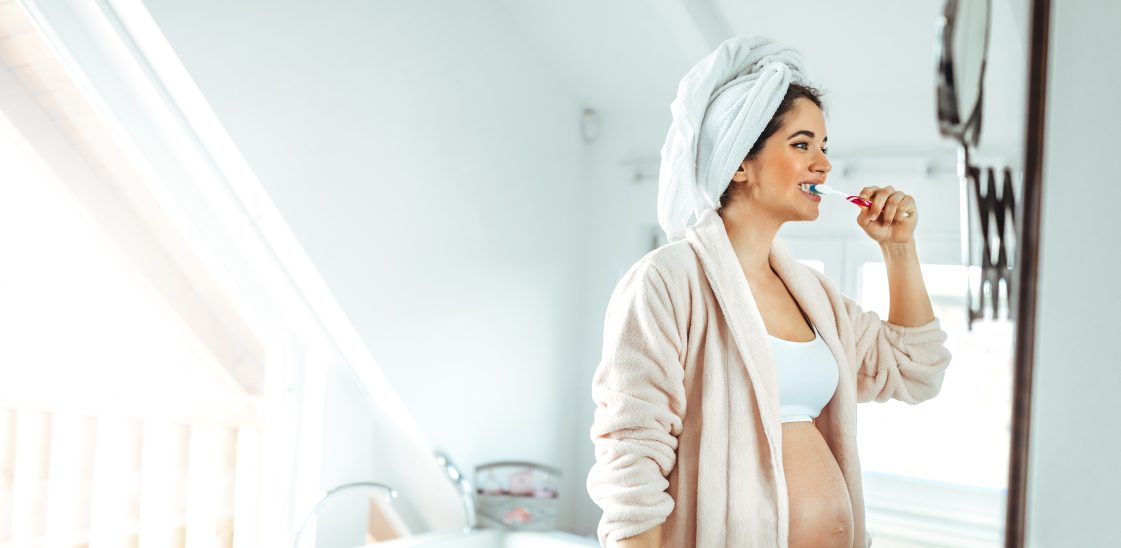 A pregnant woman brushes her teeth in the bathroom