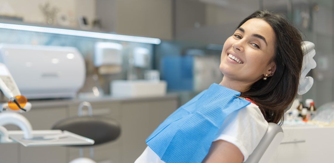 A young woman sits in a dentists’ chair, awaiting her checkup without fear.