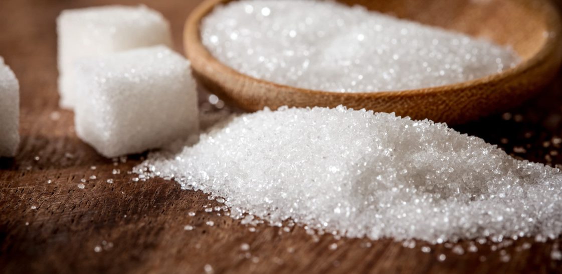 An assortment of sugar cubes and granulated sugar on a wooden surface.